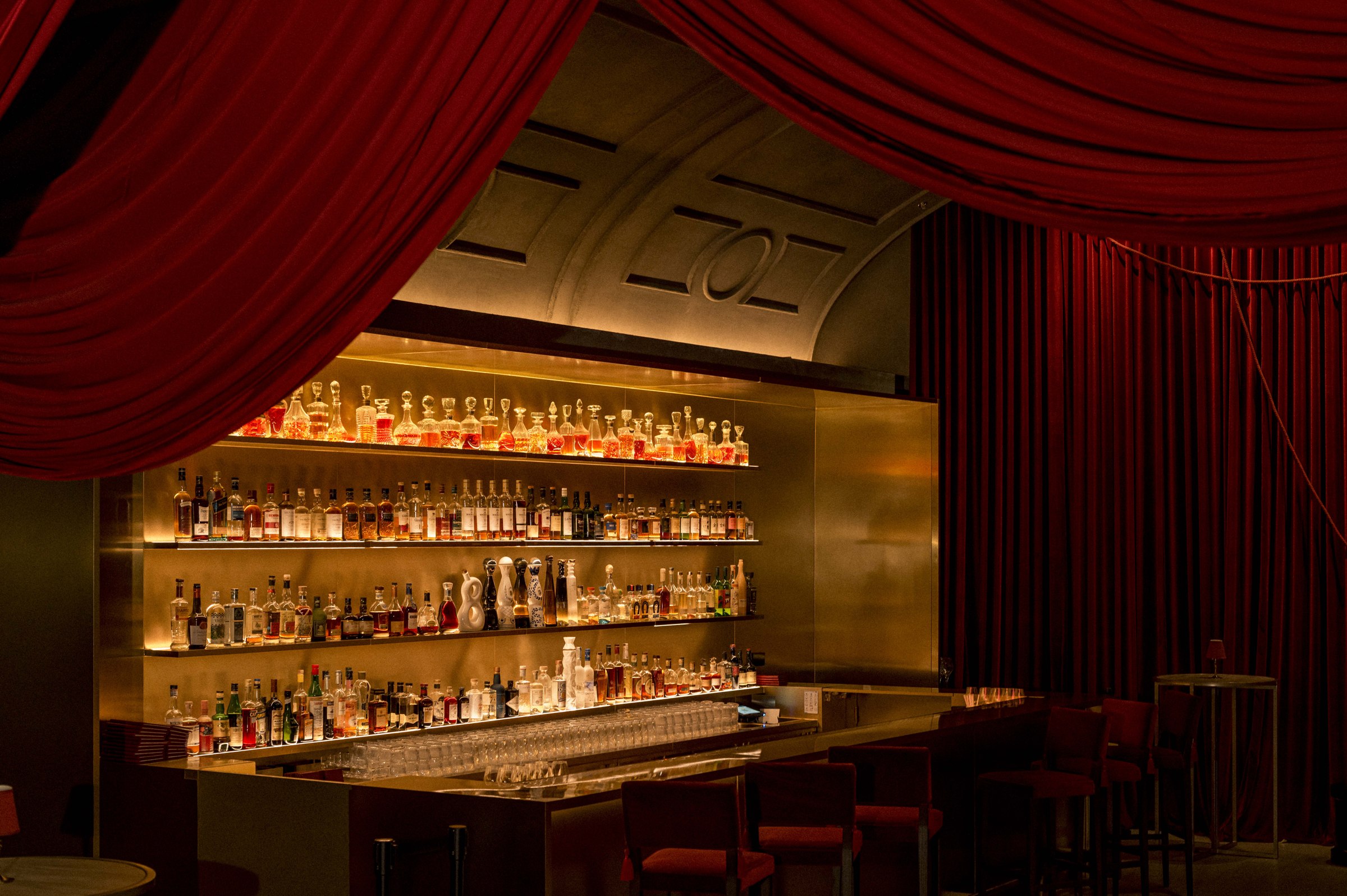 Warmly lit bar framed by red curtains